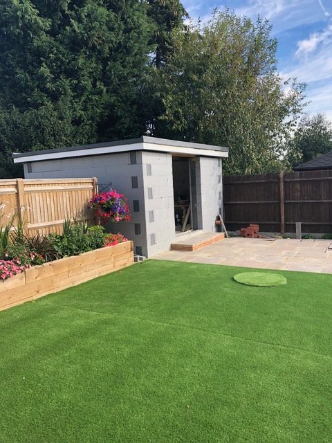 A single-storey annex shell standing at the end of a domestic back garden